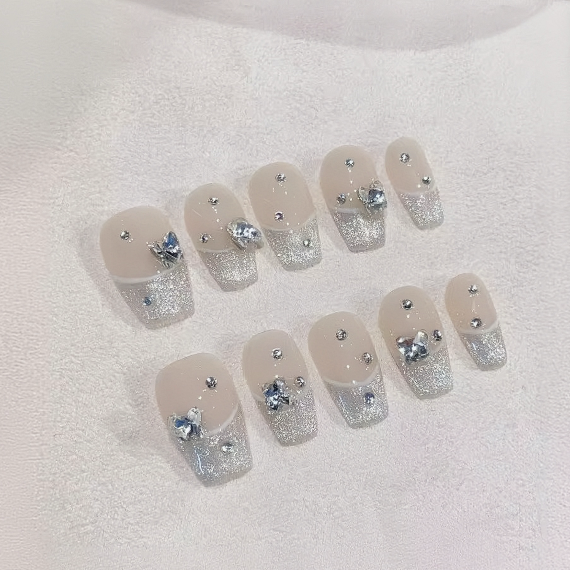 Set of nails with silver glitter and rhinestone decorations on a white background