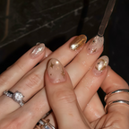 Close-up of hands with gold and clear nail polish on a dark background