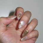 Hand with decorative nails featuring gold accents on a plain background