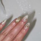 Hand with decorative nails featuring gold and star designs on a neutral background