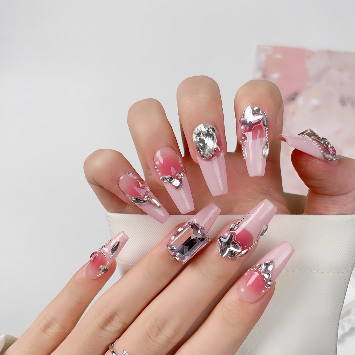 Hand with pink and silver nail art on a white background