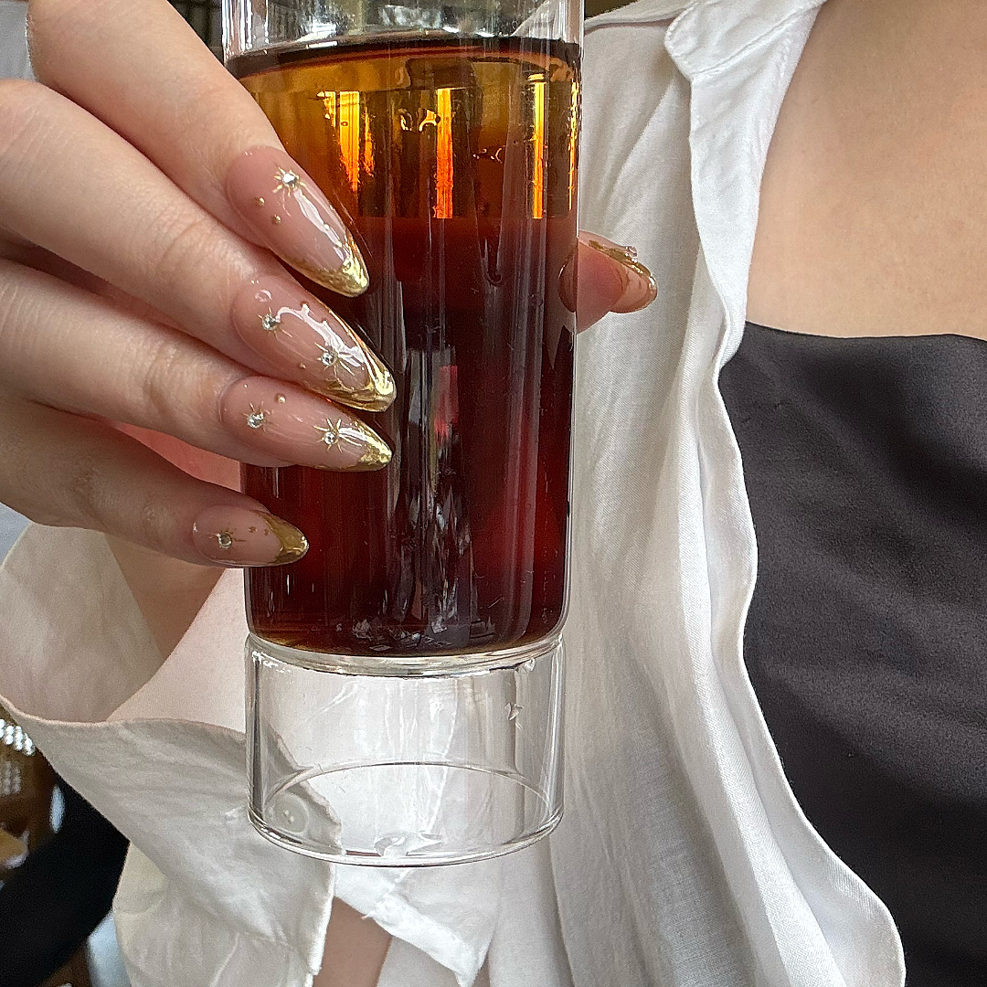 Hand holding a glass of iced tea with a blurred background