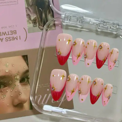 Set of pink and red gradient nails with gold decorations in a clear display case.