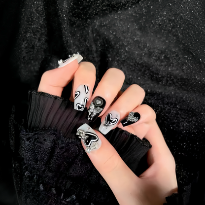 Hand with black and white nail art on a dark textured background