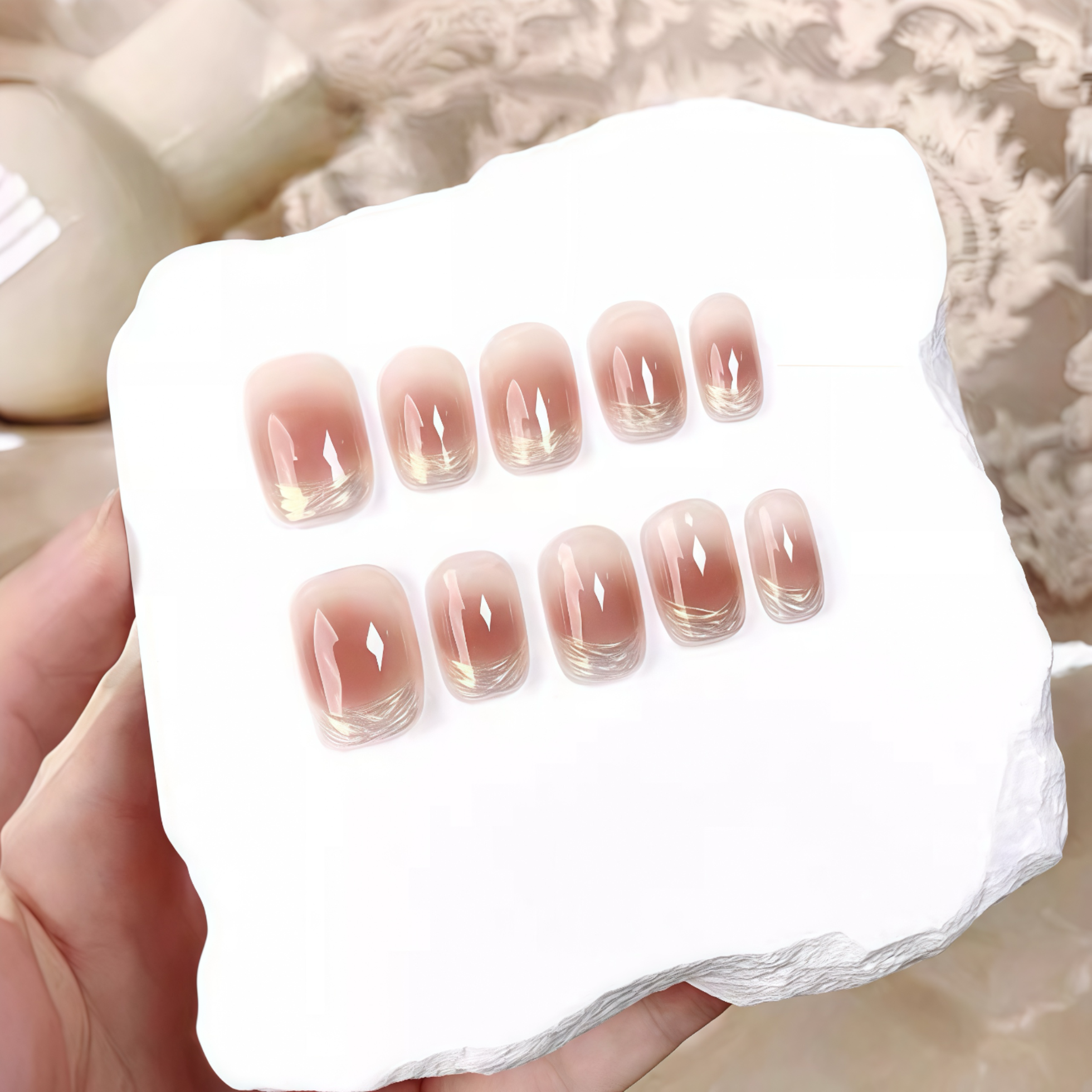 Set of gradient nail designs in a white box held by a hand.