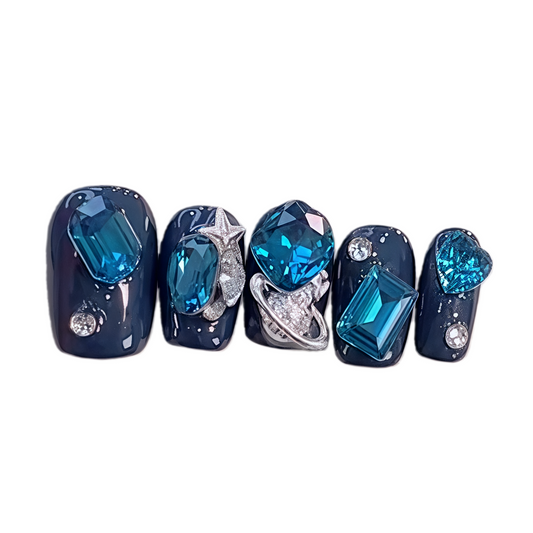 Set of false nails with blue gemstones and silver accents on a white background
