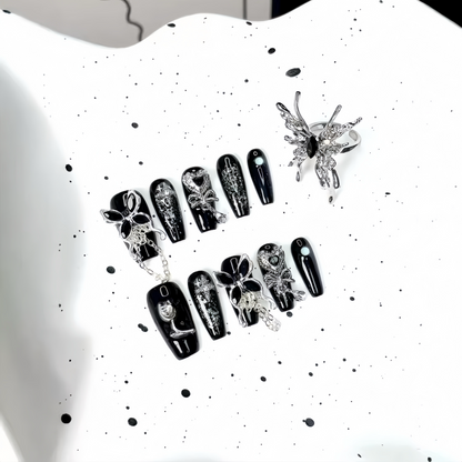 Black and white nail art designs on a white surface with a black splatter pattern.